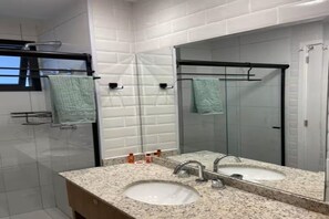 Ein Badezimmer mit zwei Waschbecken, einem Spiegel und einem Handtuchhalter.