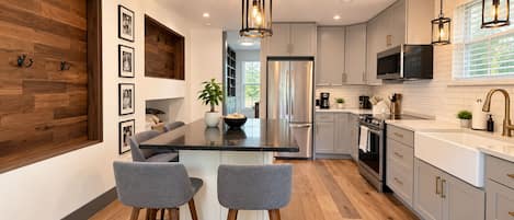 Una cocina moderna con una isla central, electrodomésticos de acero inoxidable y una zona de bar con taburetes.