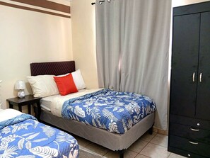 Une chambre d’hôtel avec un lit, une table de chevet, une armoire et un rideau.