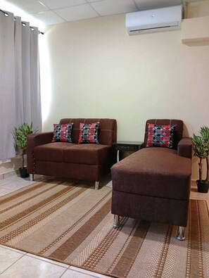 A living room with two brown sofas, patterned cushions, a striped rug, and two potted plants. - Serene 2-bedroom house in charming Juayua. (Juayua)
