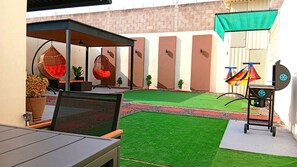 An outdoor patio with a table, chairs, hanging chairs, and a grill. - Serene 2-bedroom house in charming Juayua. (Juayua)