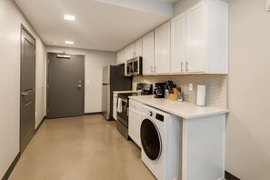 A compact kitchen with a washing machine, a microwave, and a coffee maker. - Charming Studio in Historic Five Points South #90 (Birmingham)