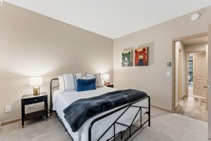 Une chambre à coucher avec un lit, des tables de chevet, une lampe et des œuvres d’art accrochées au mur.