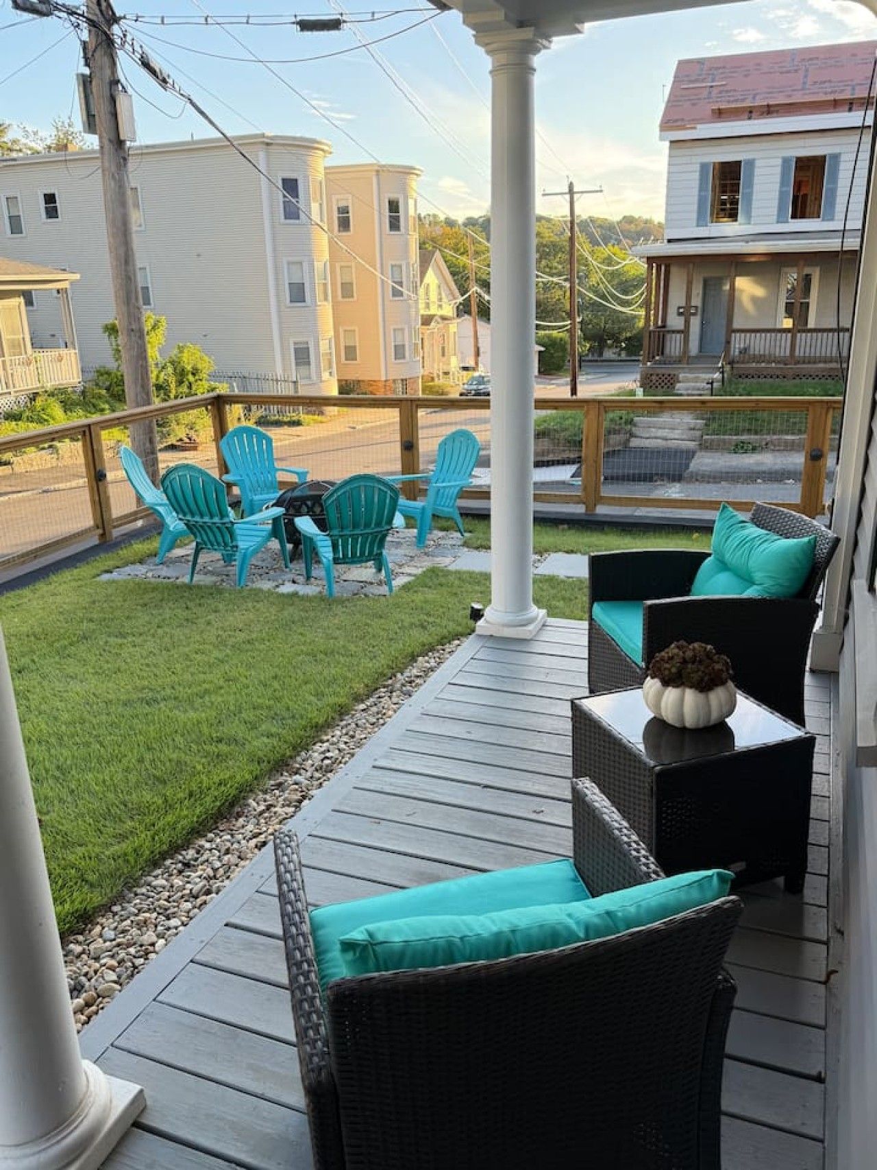 Un espace extérieur aménagé, abrité et doté de chaises et d’une table, ainsi qu’une pelouse et une vue sur les maisons voisines.
