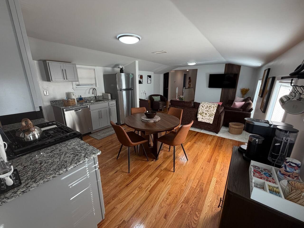 Une cuisine moderne avec un coin repas, un plancher en bois et une cuisinière intégrée.