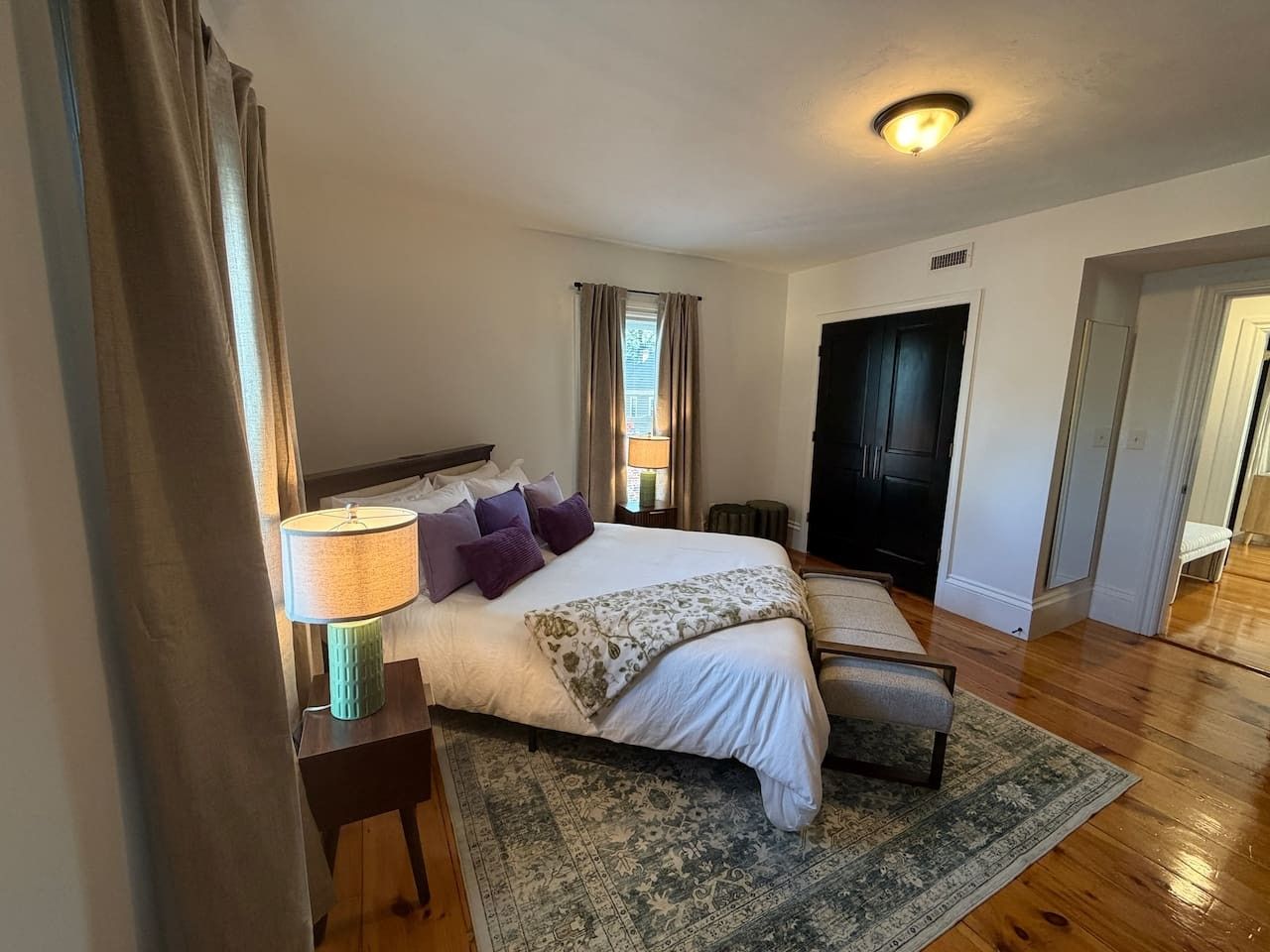 Une chambre à coucher avec un lit, une table de chevet, une lampe et un tapis à motifs.
