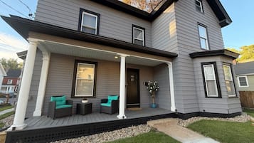A two-story house with a covered porch, a front door, and a mailbox.