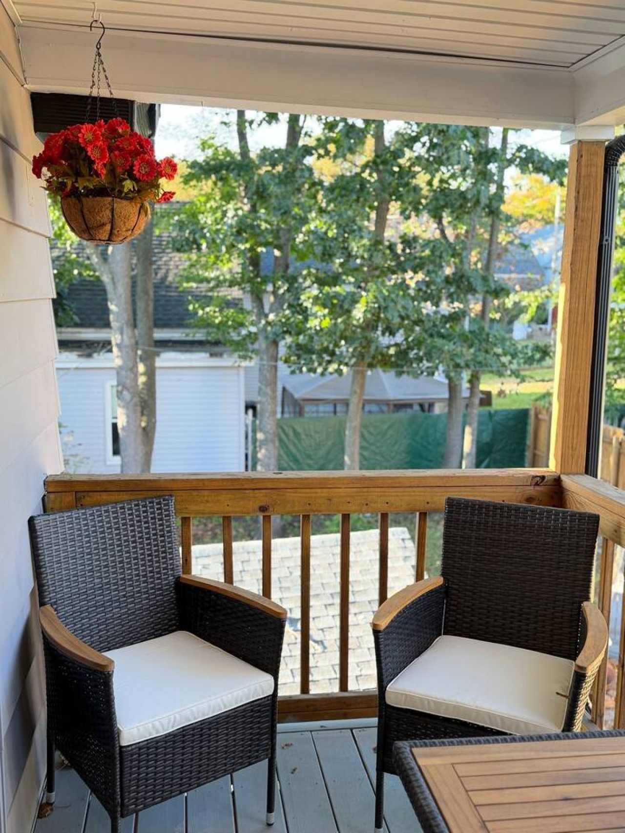 A covered outdoor seating area with wicker chairs and a hanging flower basket.