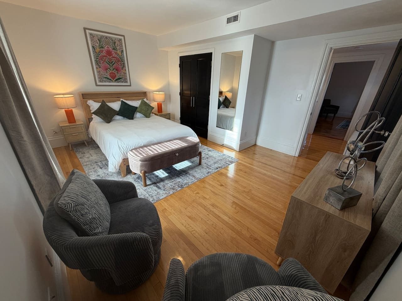 Un dormitorio moderno con cama, mesitas de noche, un banco y un armario.