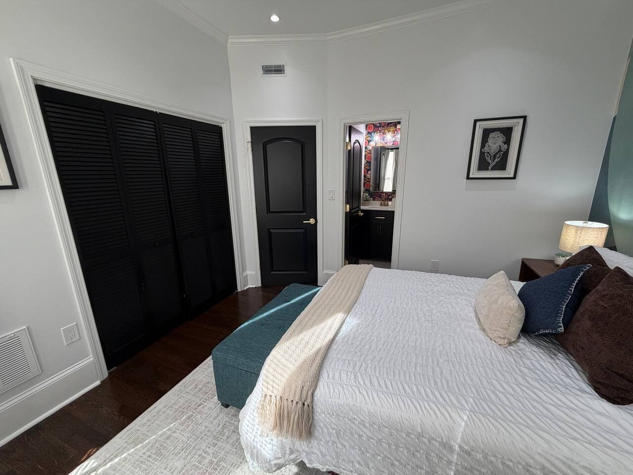 A bedroom with a bed, a closet, a door, and a wall-mounted picture.