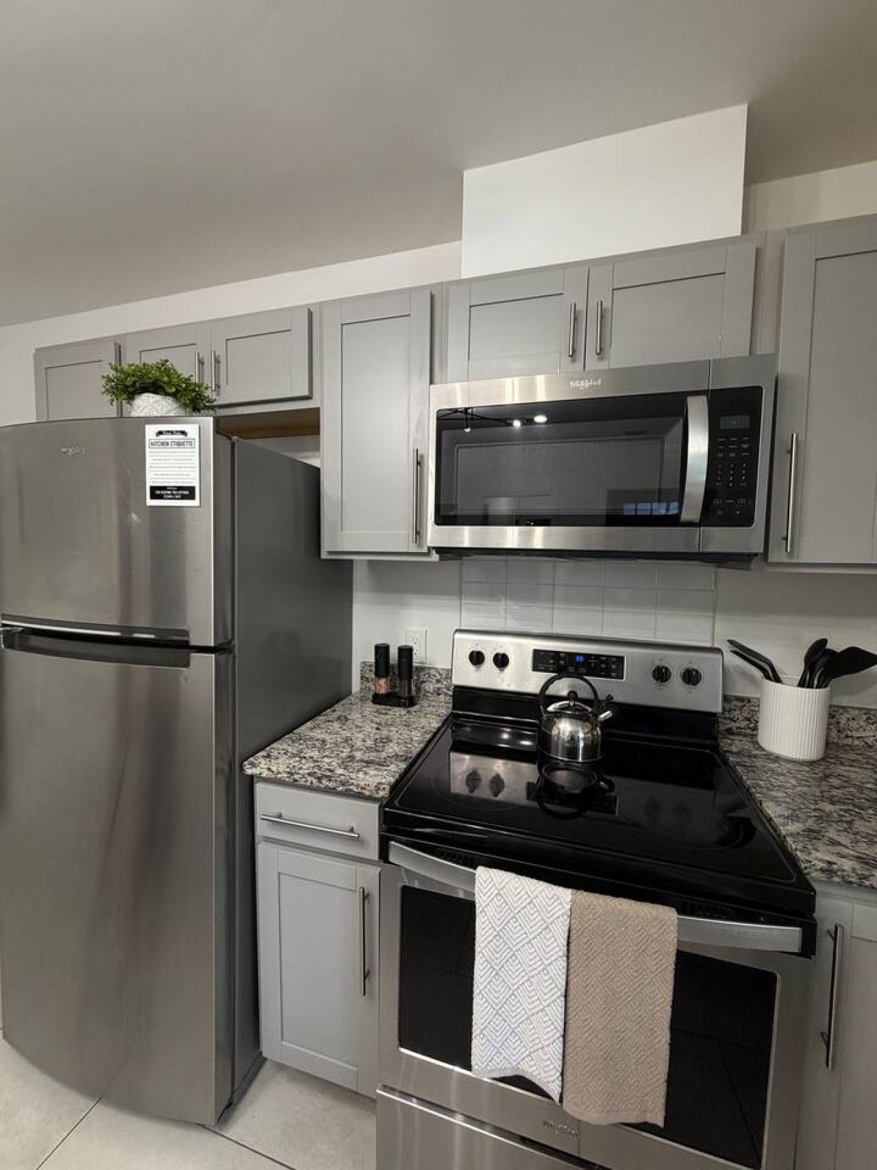 A modern kitchen with stainless steel appliances, including a refrigerator, microwave, and stove.