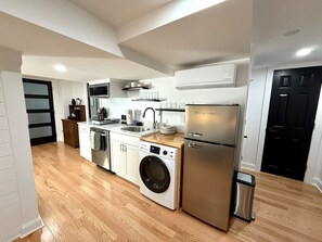 A modern kitchen with a stainless steel refrigerator, built-in oven, and a washing machine. - Modern Studio Suite -Private Entrance -W/D and A/C (Lowell)
