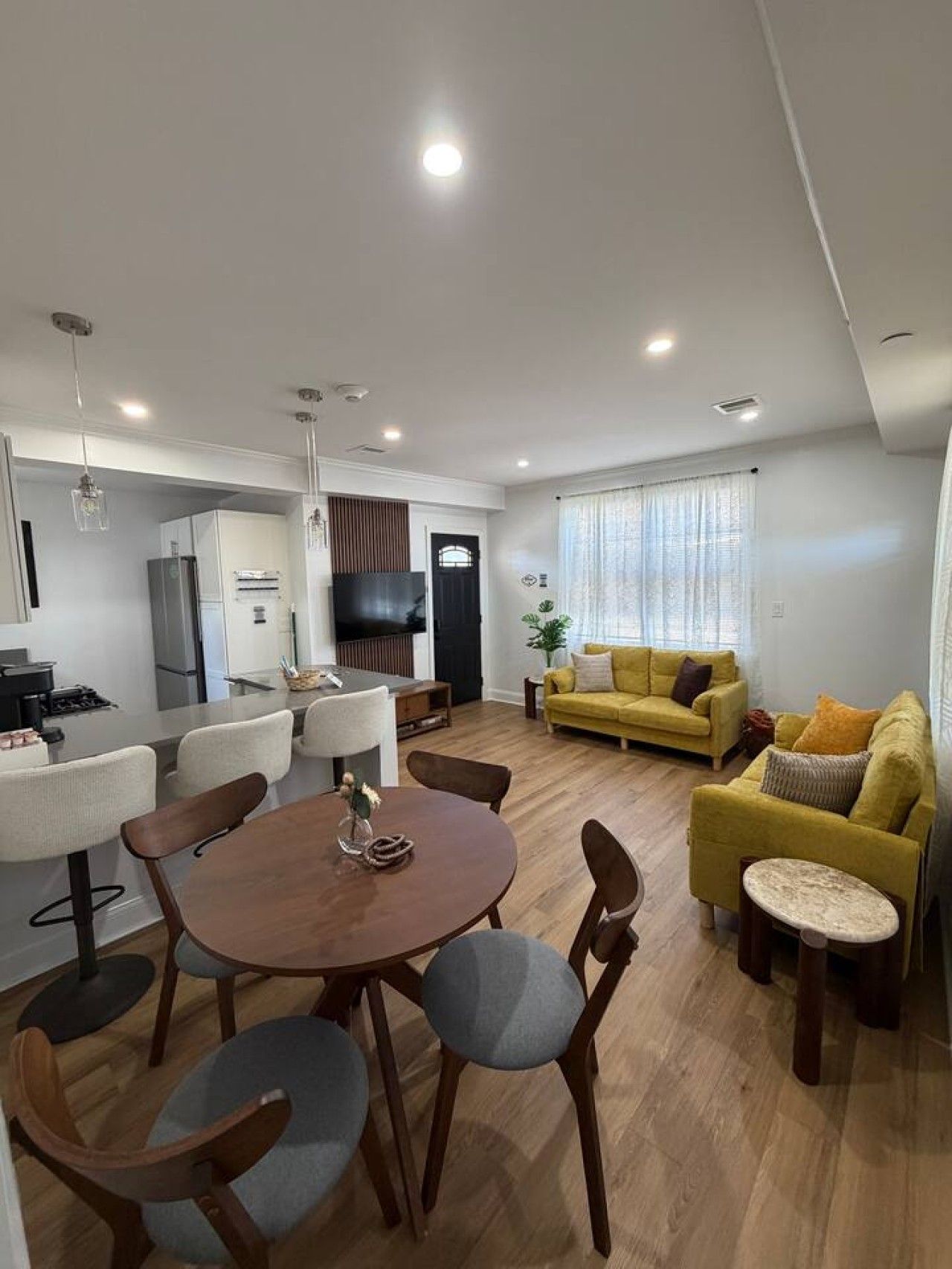 Una sala de estar moderna con comedor, sofá y televisor.