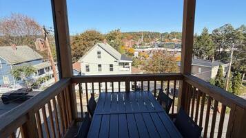 Un espacio al aire libre techado con una mesa y sillas, con vista a un barrio residencial.