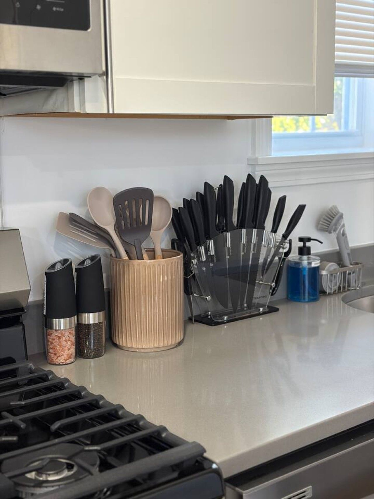 Una encimera de cocina con estufa, especiero y portalatazos.