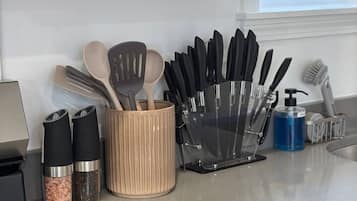 Una encimera de cocina con estufa, especiero y portalatazos.