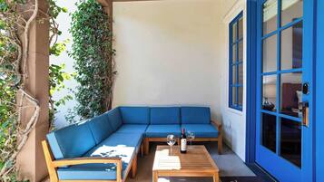 Un coin salon avec un canapé bleu, une table en bois et une bouteille de vin.