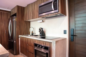 Een kleine keuken met een inbouwmagnetron, roestvrijstalen apparatuur en houten keukenkastjes.