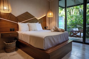 Een moderne slaapkamer met een houten hoofdbord, een groot bed, nachtkastjes, een geweven mand en een uitzicht op weelderige begroeiing door grote ramen.