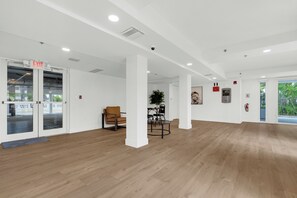 Un interior amplio con piso de madera, paredes blancas y una puerta de vidrio con la indicación 'EXIT'.