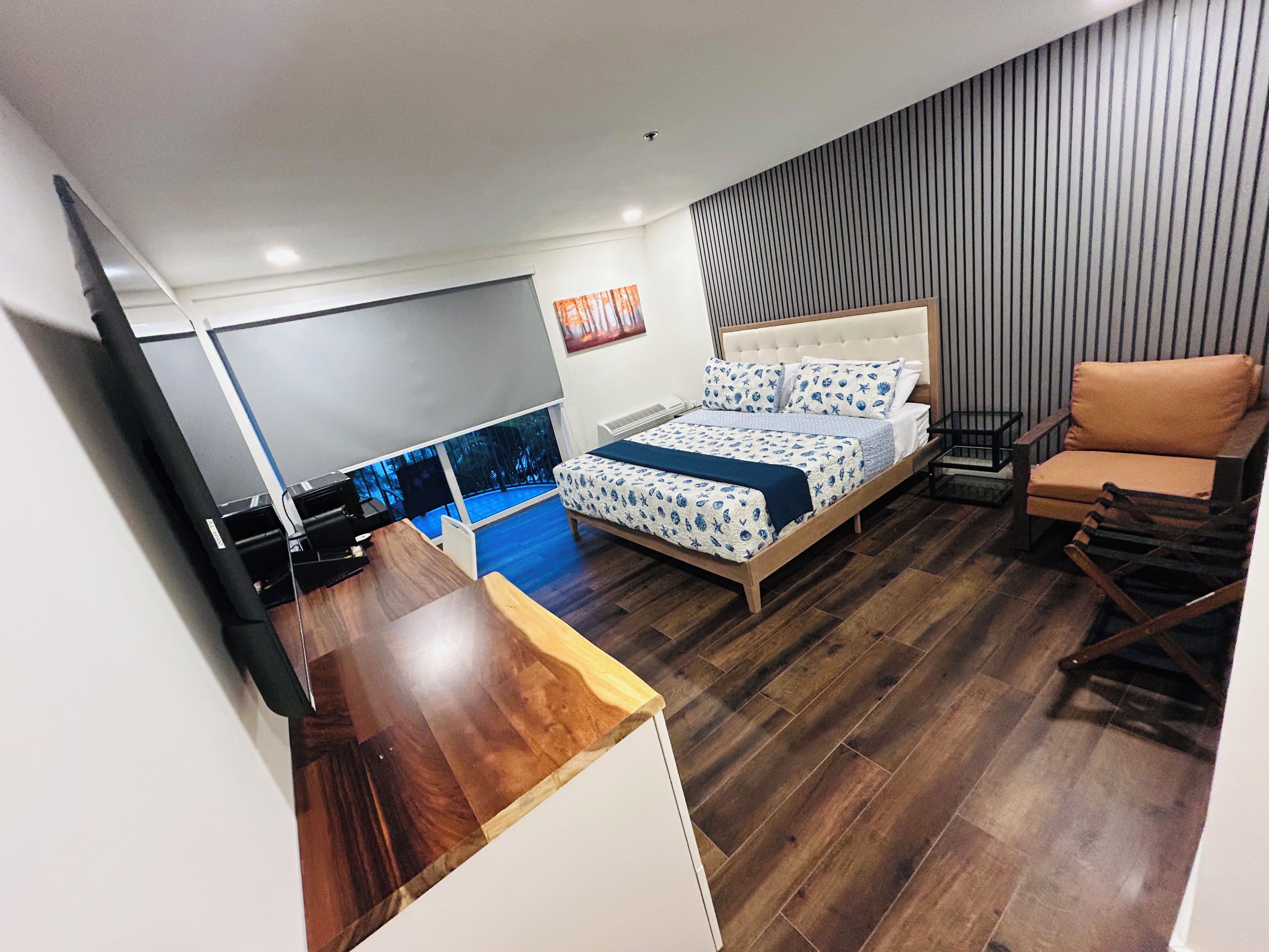 Un dormitorio con cama, escritorio, silla y televisión.