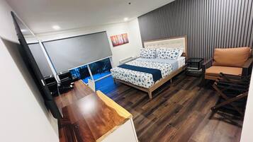 Un dormitorio con cama, escritorio, silla y televisión.