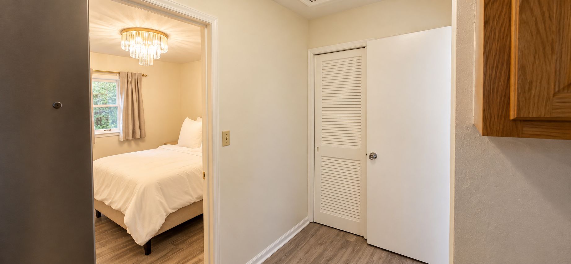 A bedroom with a bed, a door, and a chandelier.