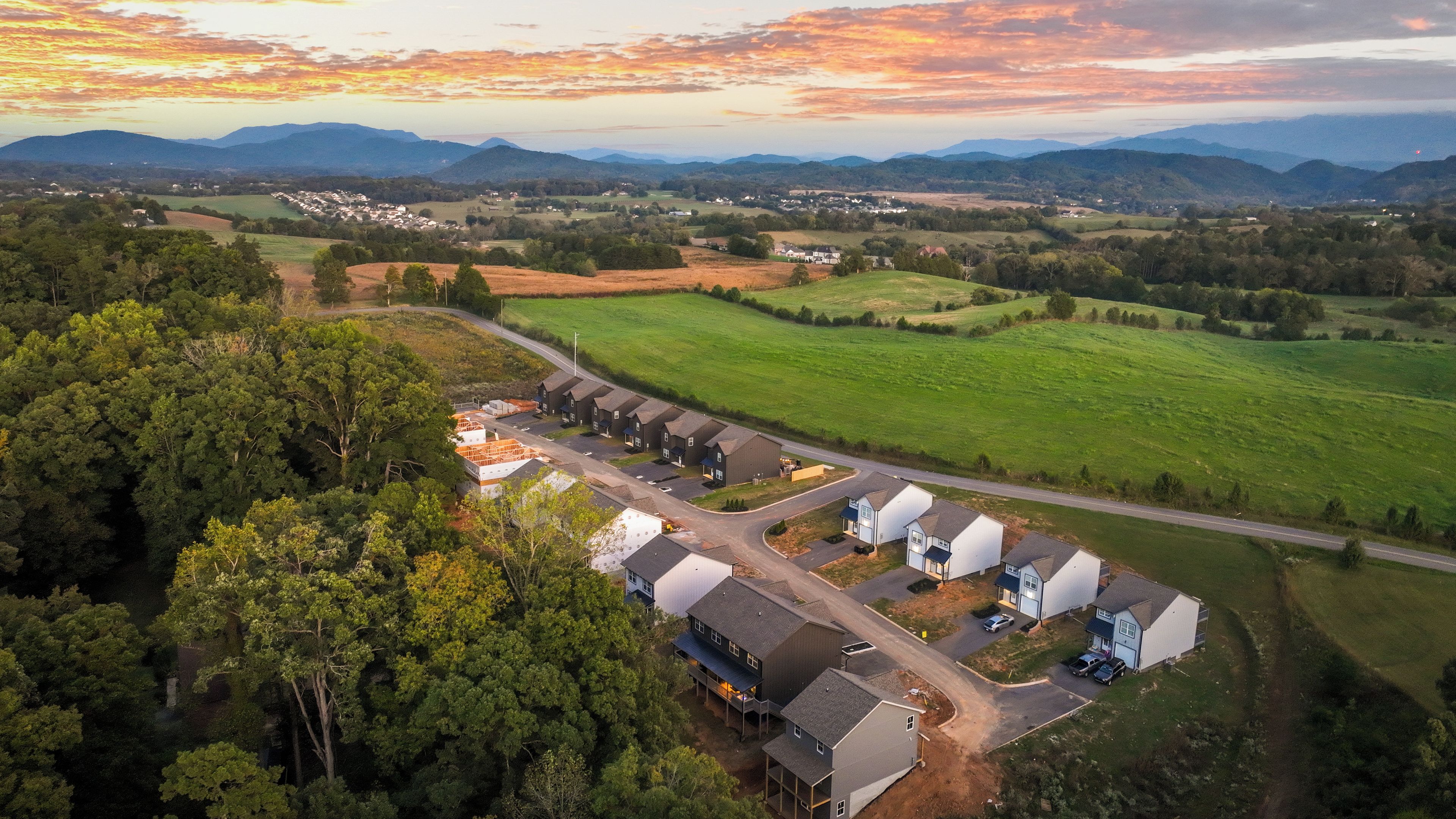 An aerial view of a residential area with houses, roads, and surrounding greenery.