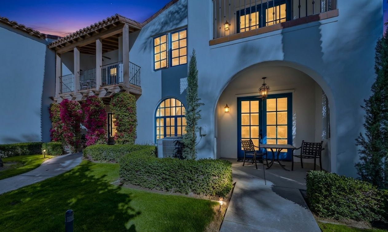 A two-story house with a balcony, large windows, and a well-lit entrance.