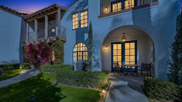 A two-story house with a balcony, large windows, and a well-lit entrance.