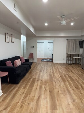 A spacious living area with a black sofa, a ceiling fan, and a wooden floor. - 3 Bd 2 Ba Apt Chinatown (Philadelphia)