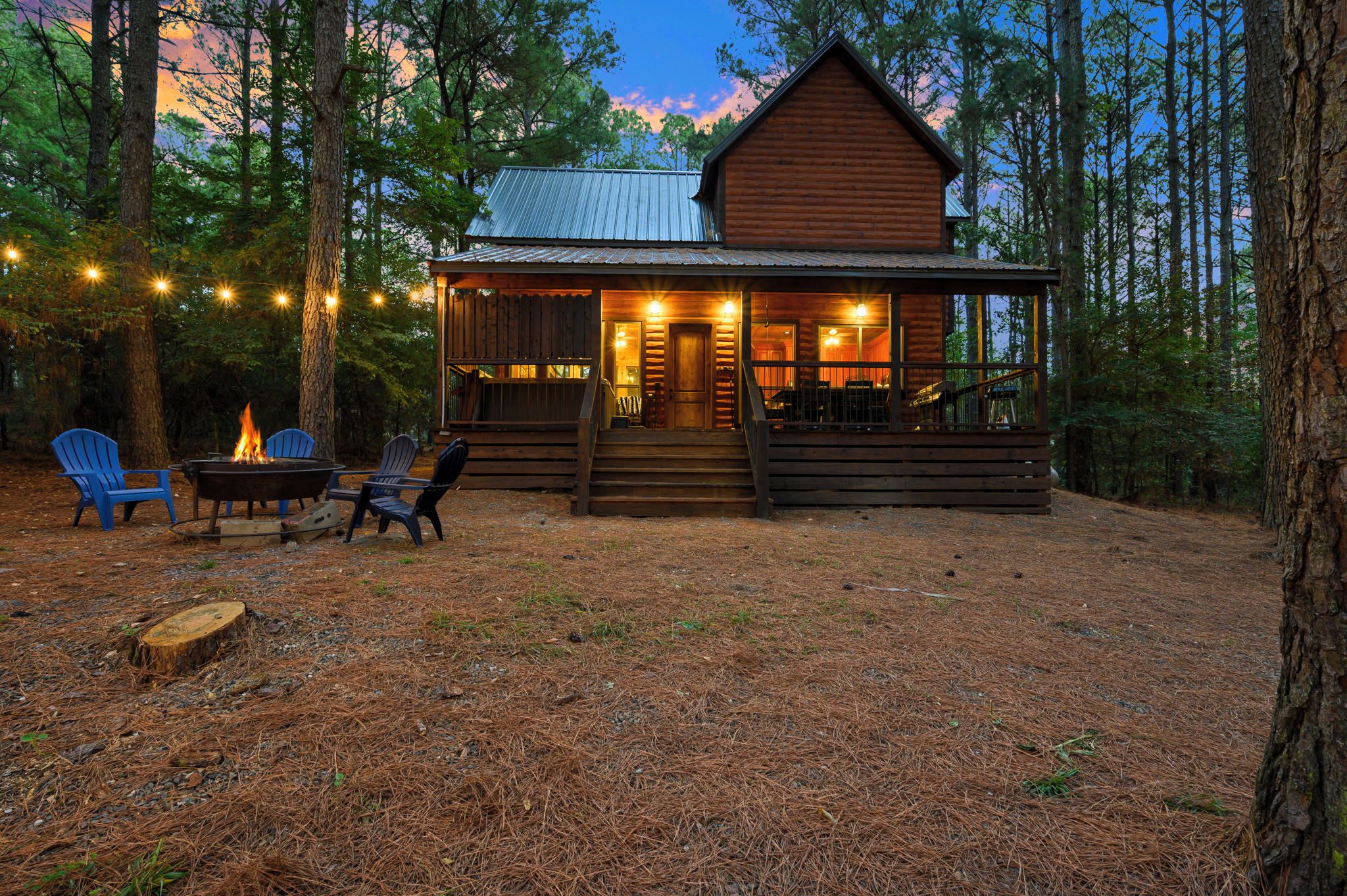 A cabin with a porch, outdoor seating, and a fire pit.