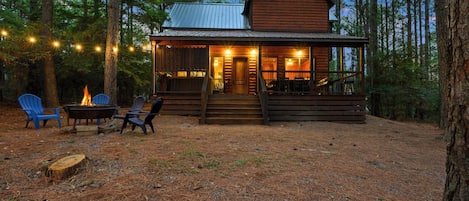 A cabin with a porch, outdoor seating, and a fire pit.