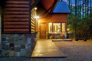 A log cabin with a stone foundation, a wooden deck, and a stone fireplace. - 4 Bedroom Cabin neighboring a main entrance to Beavers Bend State Park (Broken Bow)