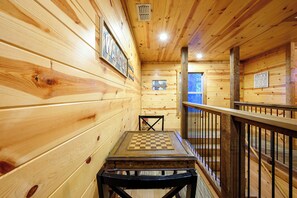 A wooden cabin interior with a checkered table, a window, and a sign with cabin rules. - 4 Bedroom Cabin neighboring a main entrance to Beavers Bend State Park (Broken Bow)