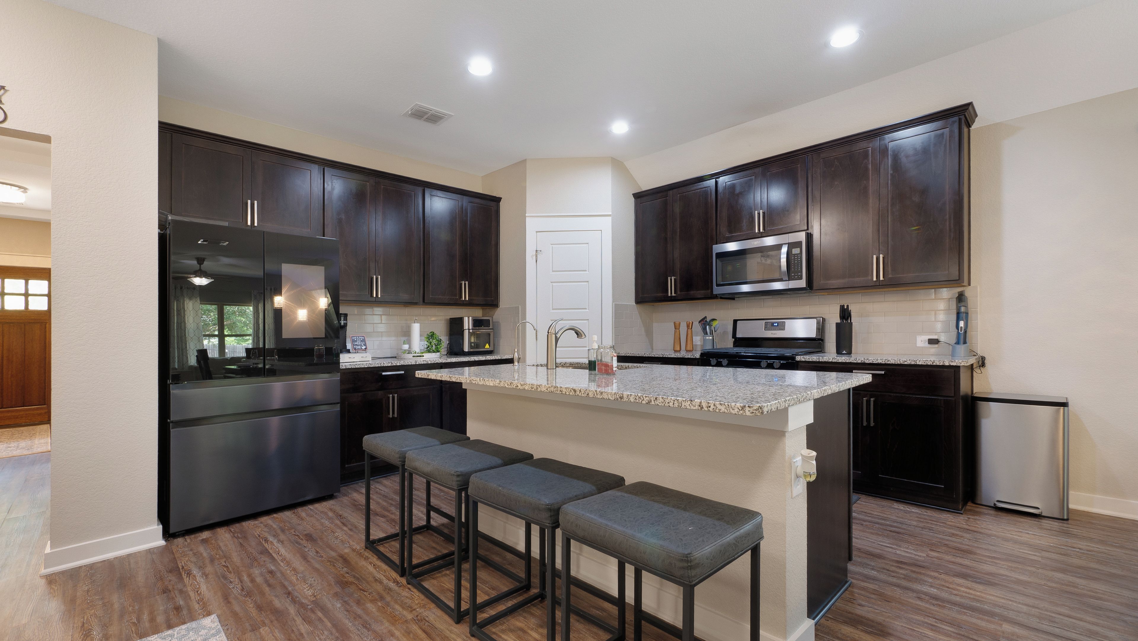 A modern kitchen with dark wood cabinets, stainless steel appliances, and a granite countertop.
