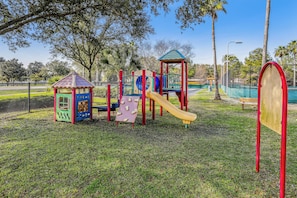 A playground with a slide, climbing structures, and a small house. - Escape to The Palms | Gulf Views, Resort Pool & Beach Gear (Destin)