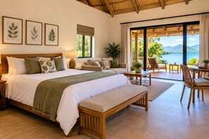Un dormitorio amplio con una cama grande, un sofá, una mesa de comedor y vistas a un lago.