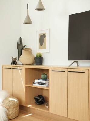 A modern living room with a wooden cabinet, a television, and decorative items. - Modern guest house with incredible light, open floor plan, office and deck (Boulder)