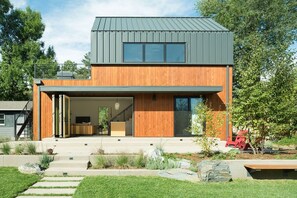 A modern two-story house with a large open garage, a staircase, and a well-maintained garden. - Modern guest house with incredible light, open floor plan, office and deck (Boulder)