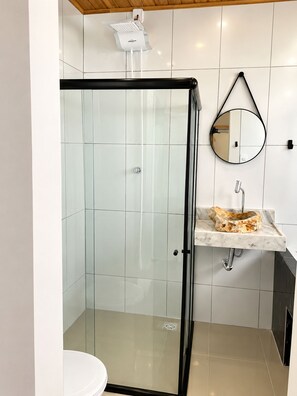 A modern bathroom with a glass-enclosed shower, a marble sink, and a round mirror. - Pousada Francês suites (Marechal Deodoro)