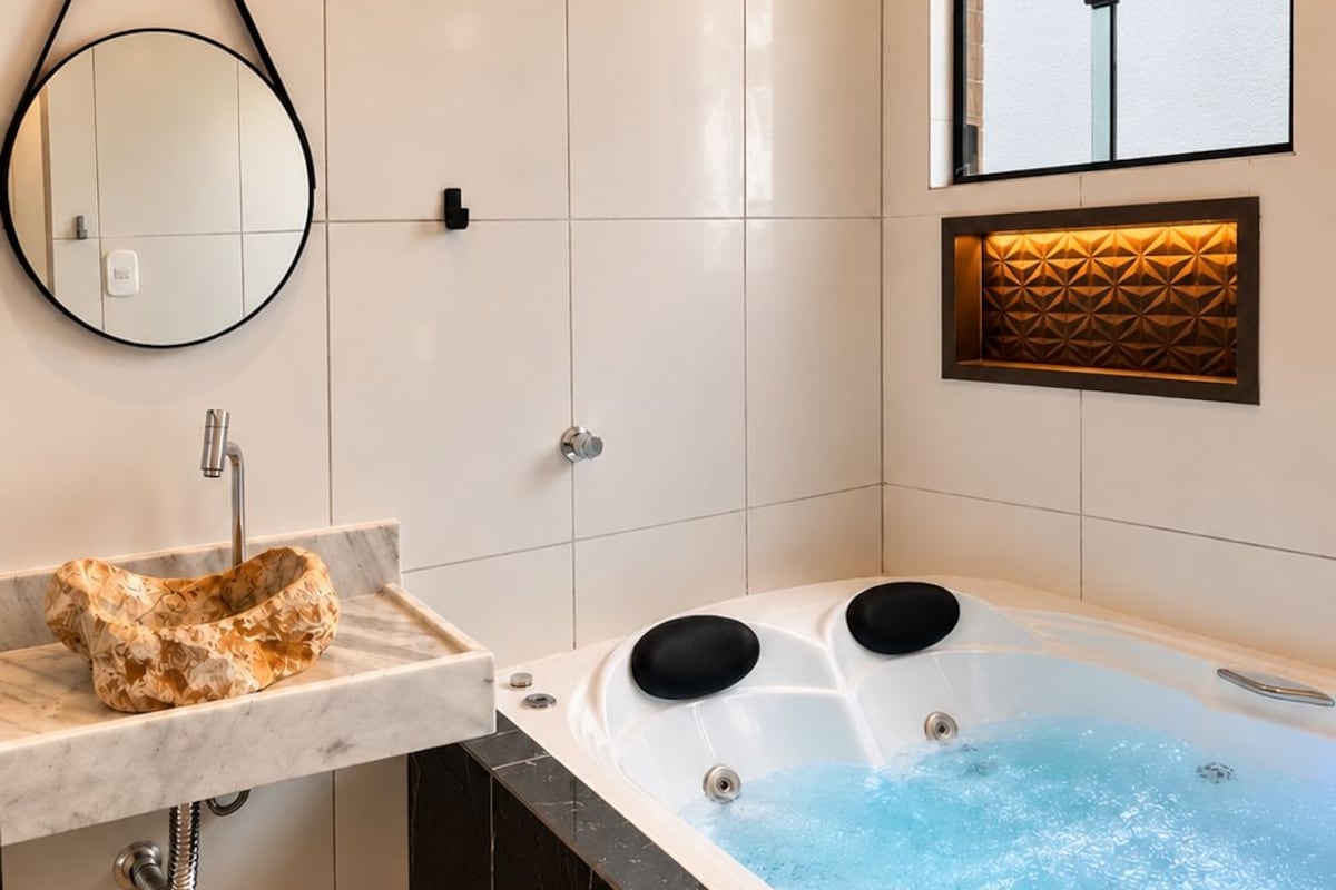 A modern bathroom with a marble sink, a bathtub with jets, and a wall-mounted mirror.
