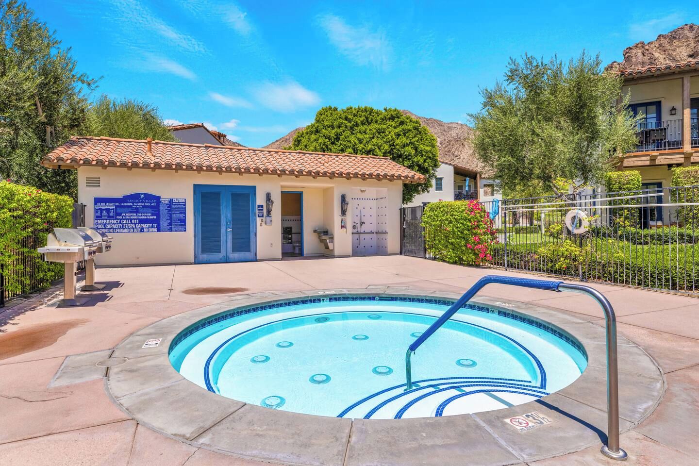 A swimming pool with a lifeguard stand and a building with a blue door in the background.