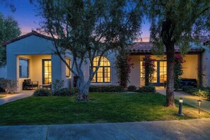 A two-story house with a well-maintained lawn, a patio with outdoor furniture, and a large arched window. - Fabulous King Studio Legacy Villa near Pool (B) (La Quinta)