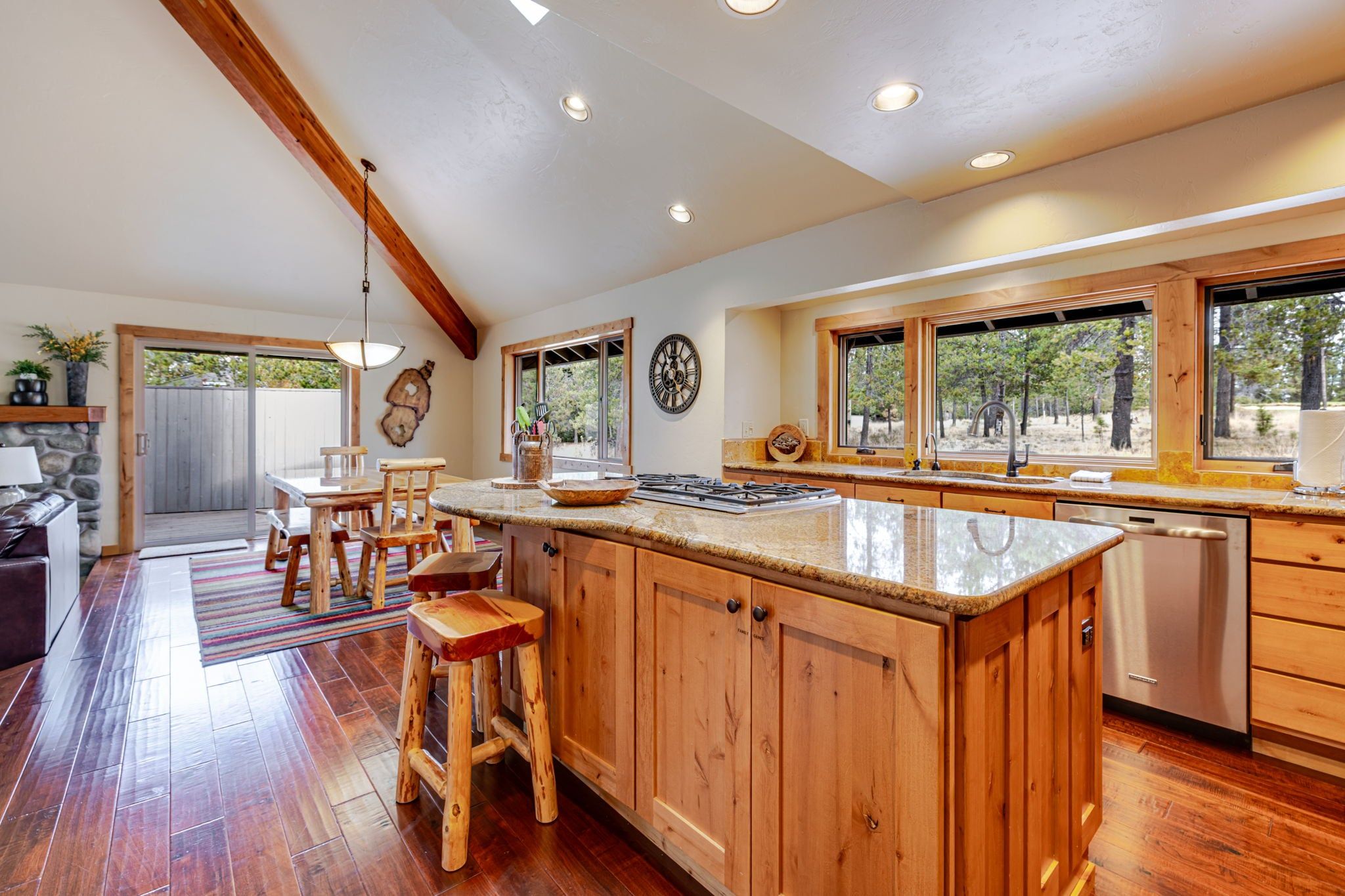 A spacious kitchen with wooden cabinets, a large island, and a view of the outdoors through the windows.