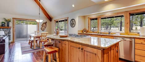 A spacious kitchen with wooden cabinets, a large island, and a view of the outdoors through the windows.