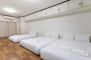 A hotel room with three beds, a wooden floor, and a ceiling with recessed lighting. - Akatsuki Yado Tatsumikita (Osaka, Ikuno-ku)