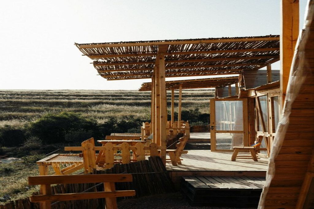 A wooden deck with seating and a thatched roof structure.