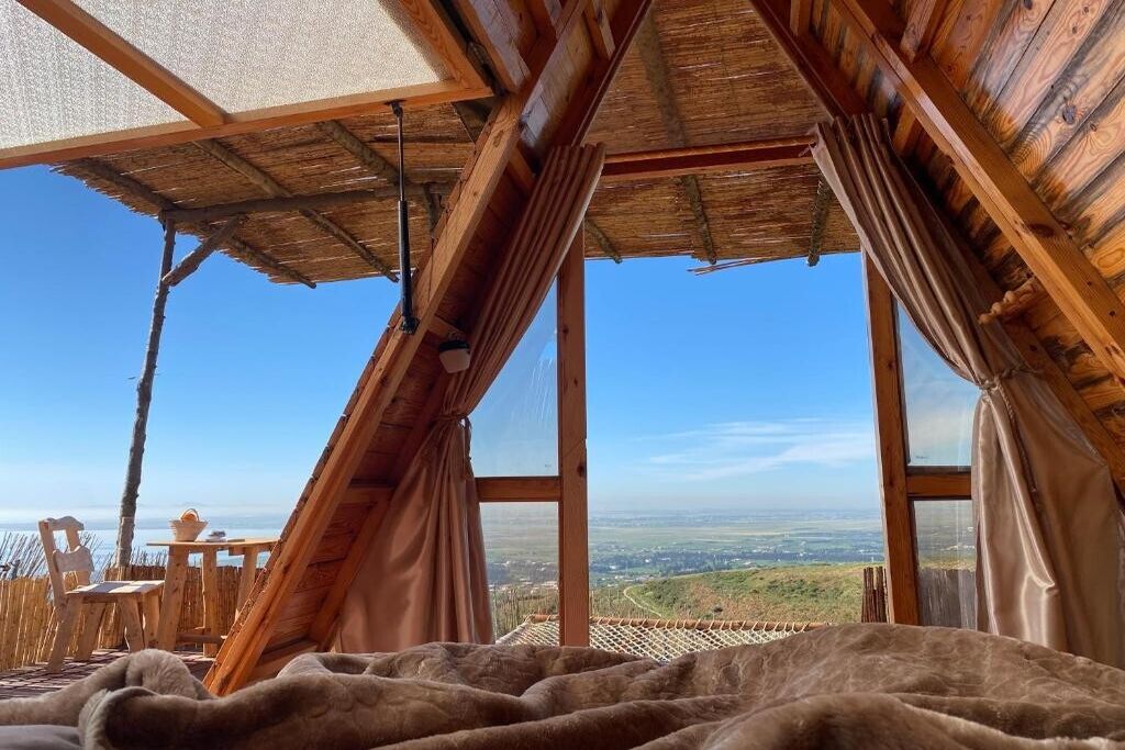 A cozy room with a wooden ceiling, large windows, and a view of the landscape.