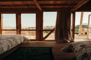 Una habitación con techo de madera, ventanas amplias, una cama y vistas al paisaje.